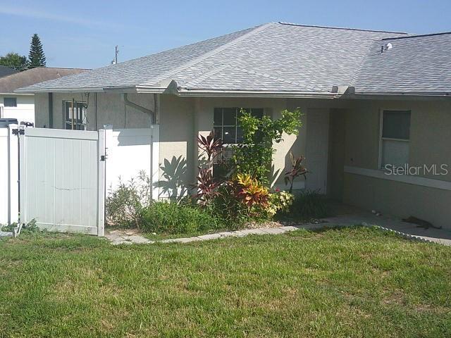 2429/2431 Quentin Ave S, Lehigh Acres, FL 33973 - view of side of home with roof with shingles, stucco siding, and a gate