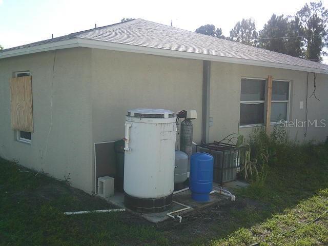 2429/2431 Quentin Ave S, Lehigh Acres, FL 33973 - view of side of property with stucco siding and a shingled roof