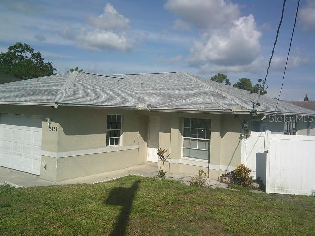 2429/2431 Quentin Ave S, Lehigh Acres, FL 33973 - back of house with a shingled roof, stucco siding, and a garage