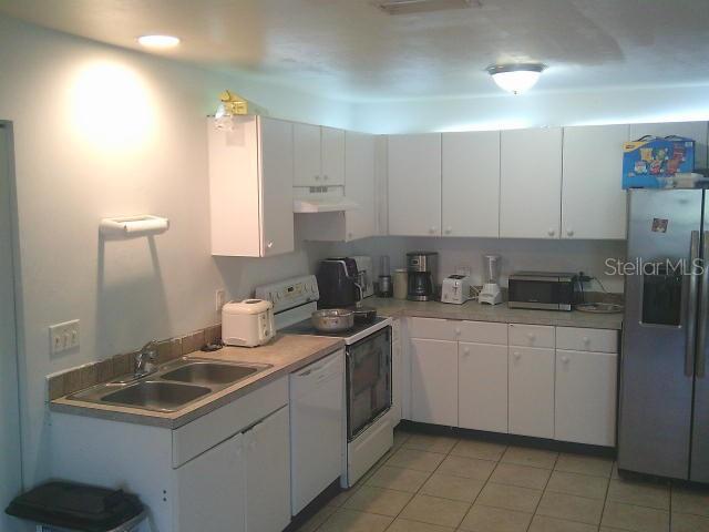 2429/2431 Quentin Ave S, Lehigh Acres, FL 33973 - kitchen featuring white appliances, under cabinet range hood, white cabinetry, and light tile patterned floors