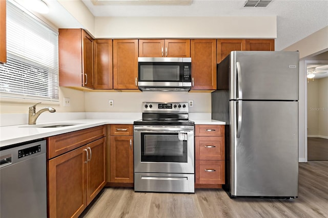 2901 Bay View Dr, Safety Harbor, FL 34695 - kitchen featuring stainless steel appliances, light wood finished floors, brown cabinetry, and light countertops