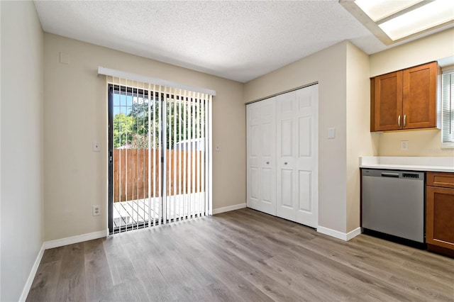 2901 Bay View Dr, Safety Harbor, FL 34695 - kitchen featuring stainless steel dishwasher, light wood-style floors, brown cabinetry, light countertops, and a textured ceiling