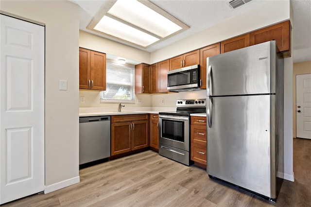 2901 Bay View Dr, Safety Harbor, FL 34695 - kitchen with appliances with stainless steel finishes, brown cabinets, light wood-type flooring, and light countertops