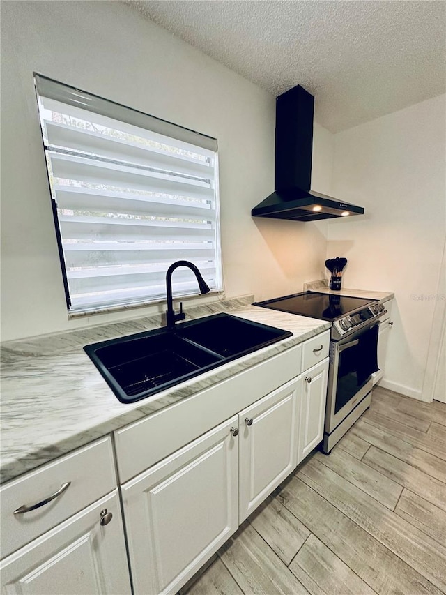 13186 Thrush St, Spring Hill, FL 34609 - kitchen featuring stainless steel range with electric cooktop, wall chimney exhaust hood, white cabinetry, light countertops, and light wood-style floors