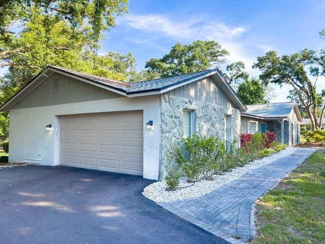 4404 Hickory Branch Ct, Brandon, FL 33511 - view of side of home featuring asphalt driveway, a garage, stone siding, and stucco siding