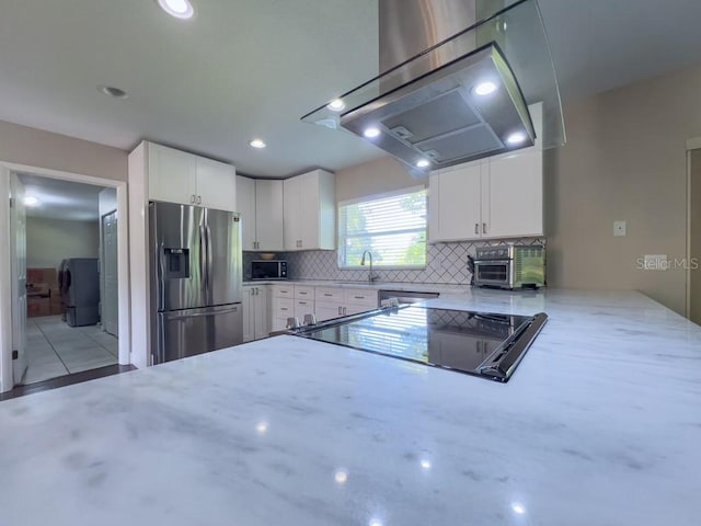 4404 Hickory Branch Ct, Brandon, FL 33511 - kitchen with appliances with stainless steel finishes, wall chimney range hood, light stone counters, decorative backsplash, and washer / dryer