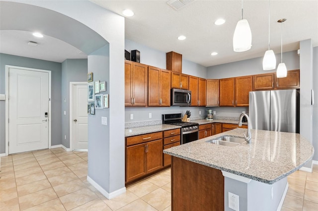 5831 Caldera Ridge Dr, Lithia, FL 33547 - kitchen with stainless steel appliances, brown cabinets, light tile patterned flooring, light stone counters, and hanging light fixtures