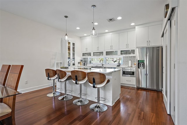 325 5th Ave S Unit 9, Saint Petersburg, FL 33701 - kitchen with appliances with stainless steel finishes, a breakfast bar area, a peninsula, dark wood-style flooring, and glass insert cabinets