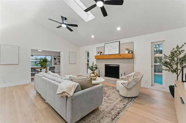 2272 Adam Ct, Palm Harbor, FL 34683 - living room featuring a ceiling fan, light wood finished floors, a fireplace, high vaulted ceiling, and healthy amount of natural light
