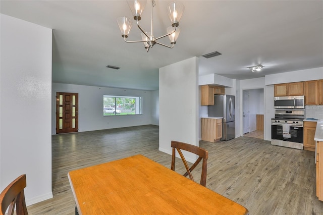 301 Carlyle Blvd, Ruskin, FL 33570 - kitchen with stainless steel appliances, light wood-style flooring, open floor plan, a chandelier, and backsplash