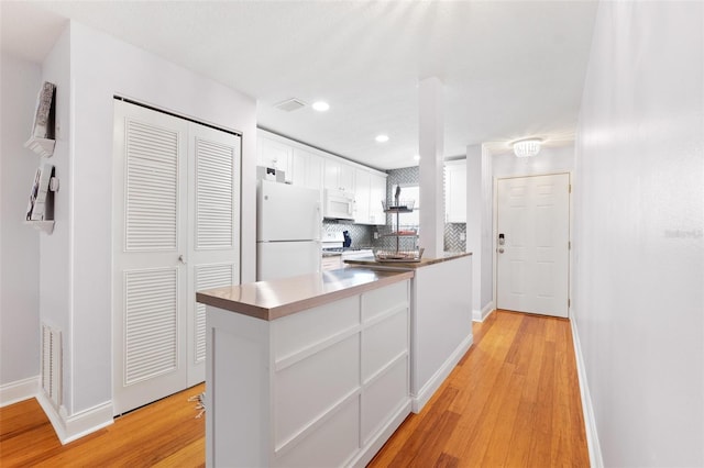 3018 59th St S Unit 405, Gulfport, FL 33707 - kitchen with white appliances, white cabinets, light wood-style flooring, decorative backsplash, and recessed lighting