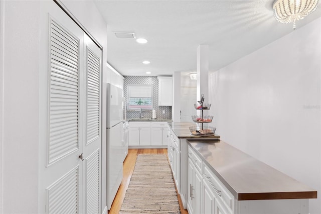 3018 59th St S Unit 405, Gulfport, FL 33707 - kitchen with light wood-style flooring, freestanding refrigerator, white cabinetry, decorative backsplash, and recessed lighting
