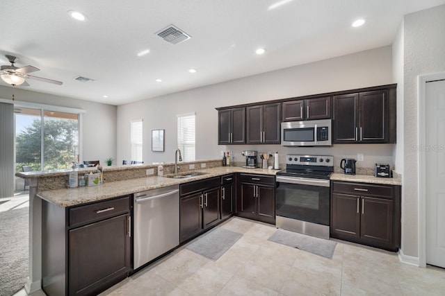1218 Grantham Dr, Sarasota, FL 34234 - kitchen with appliances with stainless steel finishes, a peninsula, ceiling fan, dark brown cabinets, and light stone counters