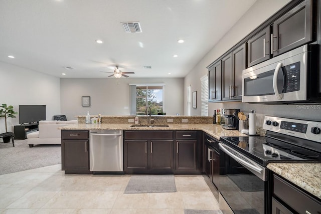 1218 Grantham Dr, Sarasota, FL 34234 - kitchen featuring stainless steel appliances, a peninsula, a ceiling fan, light stone counters, and open floor plan