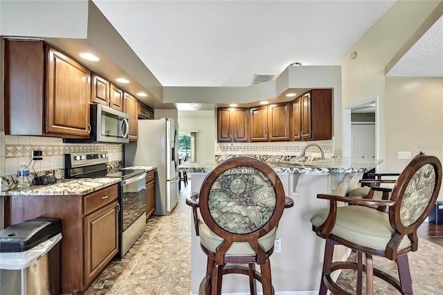 10721 N Ocean Dr, Dunnellon, FL 34434 - kitchen featuring appliances with stainless steel finishes, a breakfast bar area, decorative backsplash, and a peninsula