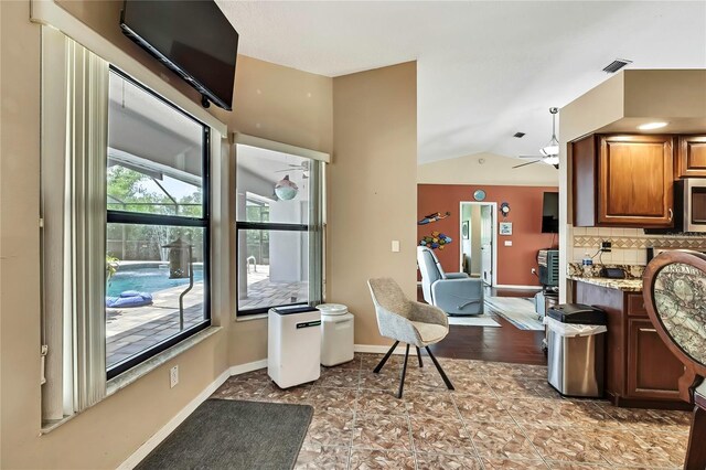 10721 N Ocean Dr, Dunnellon, FL 34434 - kitchen with lofted ceiling, tasteful backsplash, a ceiling fan, brown cabinets, and stainless steel microwave