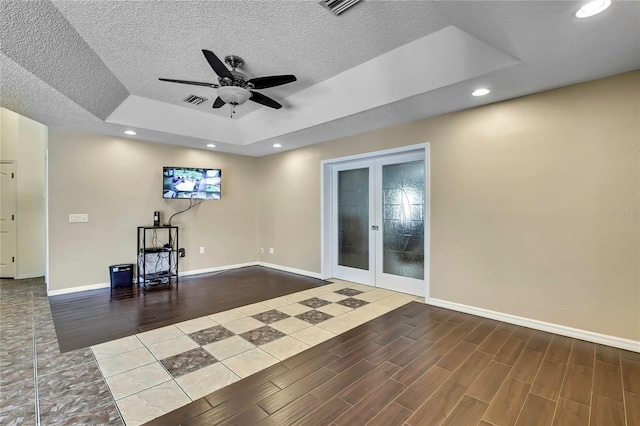 10721 N Ocean Dr, Dunnellon, FL 34434 - empty room with french doors, a ceiling fan, wood finished floors, a tray ceiling, and a textured ceiling