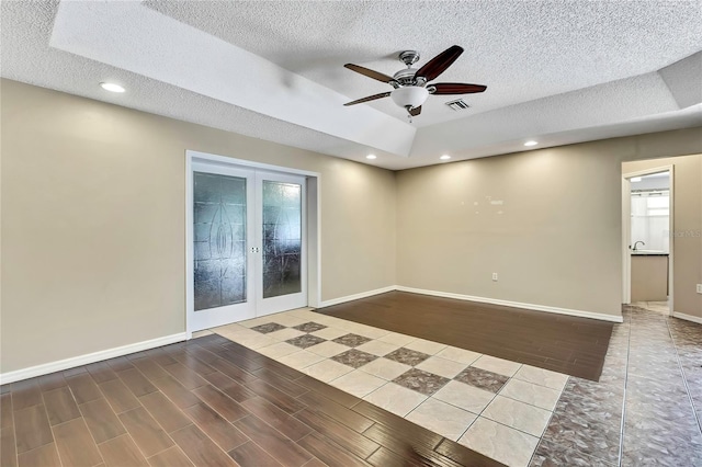 10721 N Ocean Dr, Dunnellon, FL 34434 - empty room with french doors, a textured ceiling, a ceiling fan, wood finished floors, and a raised ceiling