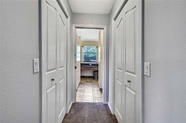 10721 N Ocean Dr, Dunnellon, FL 34434 - corridor featuring a textured ceiling, carpet, and tile patterned flooring