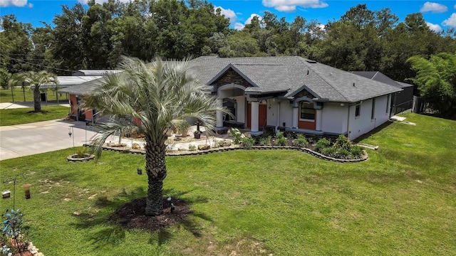 10721 N Ocean Dr, Dunnellon, FL 34434 - view of front facade featuring concrete driveway, a shingled roof, a front lawn, stucco siding, and view of wooded area