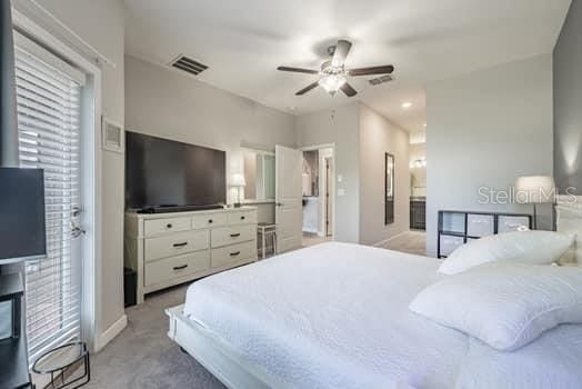 28504 Tranquil Lake Cir, Wesley Chapel, FL 33543 - bedroom with light colored carpet, ceiling fan, and ensuite bathroom