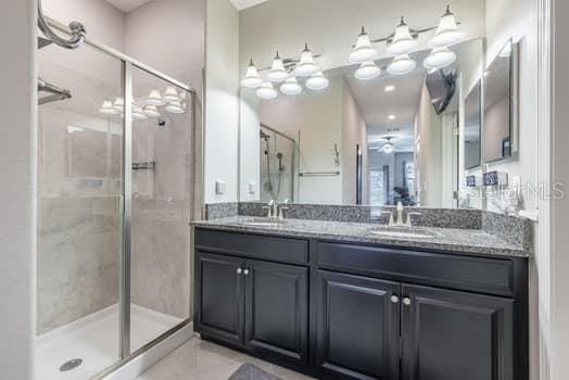 28504 Tranquil Lake Cir, Wesley Chapel, FL 33543 - full bath featuring a shower stall, double vanity, a ceiling fan, and tile patterned floors
