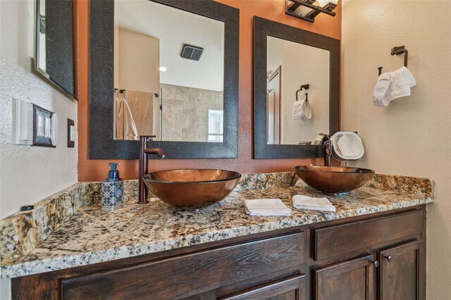 31244 Baclan Dr, Wesley Chapel, FL 33545 - bathroom with double vanity, a textured wall, and a tile shower