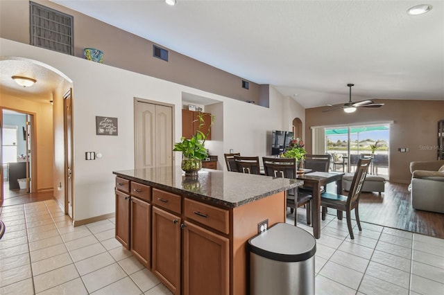 31244 Baclan Dr, Wesley Chapel, FL 33545 - kitchen with arched walkways, light tile patterned flooring, lofted ceiling, a kitchen island, and a ceiling fan