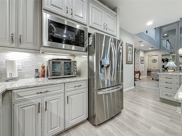 33668 Willow Point Ct, Wesley Chapel, FL 33545 - kitchen with stainless steel fridge with ice dispenser, built in microwave, decorative backsplash, light wood-style flooring, and light stone countertops