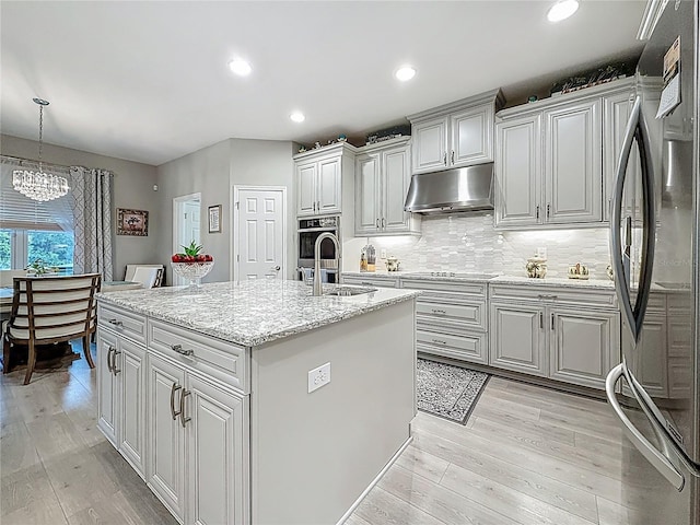 33668 Willow Point Ct, Wesley Chapel, FL 33545 - kitchen with freestanding refrigerator, under cabinet range hood, a chandelier, light wood-style flooring, and an island with sink
