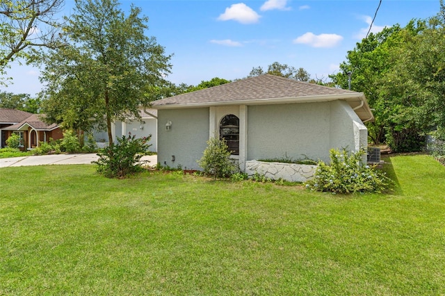 10237 Carrin Rd, Spring Hill, FL 34608 - view of front of home with stucco siding, driveway, a front lawn, and roof with shingles