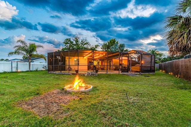 1910 Montego Ct, Oldsmar, FL 34677 - yard at dusk with a fenced backyard, a fire pit, and glass enclosure