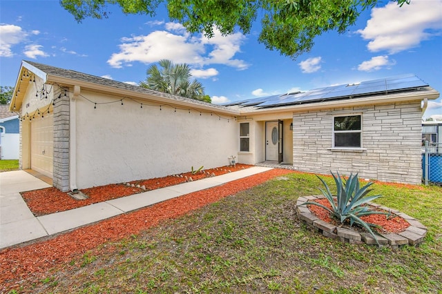 1910 Montego Ct, Oldsmar, FL 34677 - ranch-style house featuring stucco siding, roof mounted solar panels, an attached garage, stone siding, and driveway