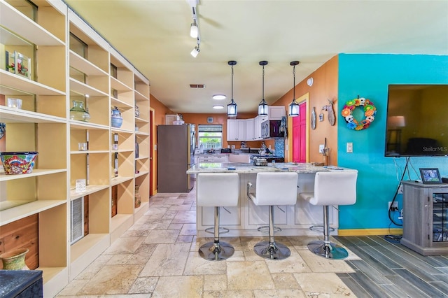 1910 Montego Ct, Oldsmar, FL 34677 - kitchen with freestanding refrigerator, a peninsula, a kitchen bar, pendant lighting, and stone tile flooring