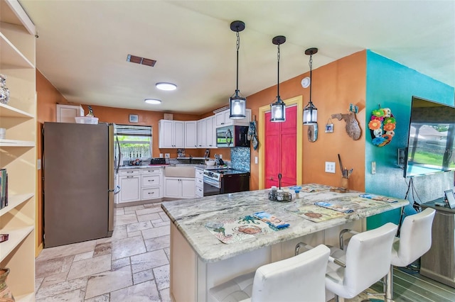 1910 Montego Ct, Oldsmar, FL 34677 - kitchen featuring stainless steel appliances, white cabinetry, light stone counters, stone tile flooring, and pendant lighting