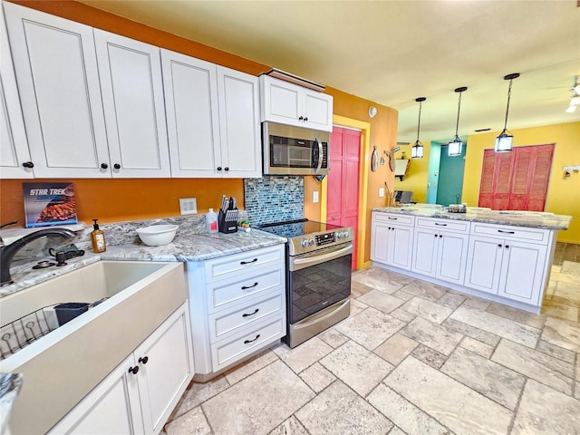 1910 Montego Ct, Oldsmar, FL 34677 - kitchen featuring appliances with stainless steel finishes, stone tile floors, white cabinetry, and decorative light fixtures