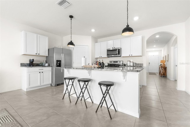 9098 Forge Breeze Loop, Wesley Chapel, FL 33545 - kitchen with stainless steel appliances, arched walkways, light tile patterned floors, a kitchen bar, and white cabinets
