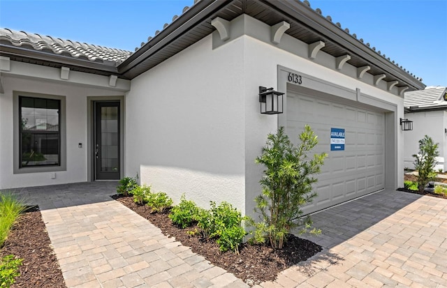6133 Wire Grass Ct, Nokomis, FL 34275 - entrance to property with a tiled roof, stucco siding, a garage, and decorative driveway