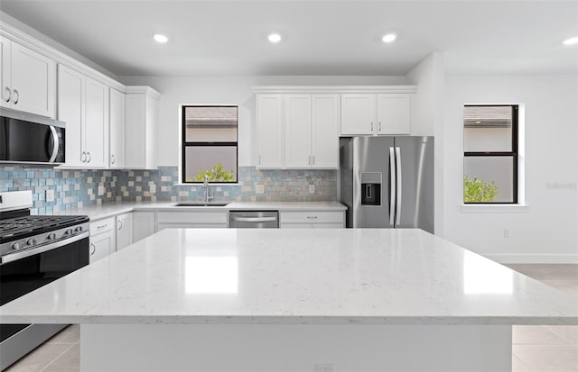 6133 Wire Grass Ct, Nokomis, FL 34275 - kitchen with stainless steel appliances, a kitchen island, decorative backsplash, white cabinetry, and light stone countertops