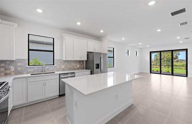 6133 Wire Grass Ct, Nokomis, FL 34275 - kitchen with appliances with stainless steel finishes, backsplash, a kitchen island, white cabinetry, and recessed lighting