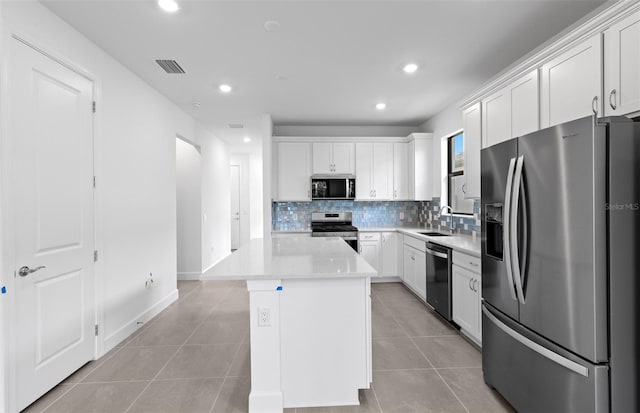 6133 Wire Grass Ct, Nokomis, FL 34275 - kitchen featuring appliances with stainless steel finishes, tasteful backsplash, a center island, light tile patterned floors, and recessed lighting