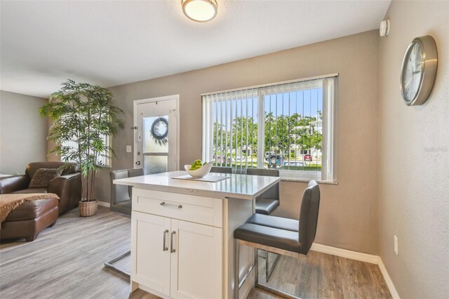 8080 112th St Unit 108, Seminole, FL 33772 - kitchen with light wood-style floors, white cabinetry, a kitchen breakfast bar, light countertops, and open floor plan
