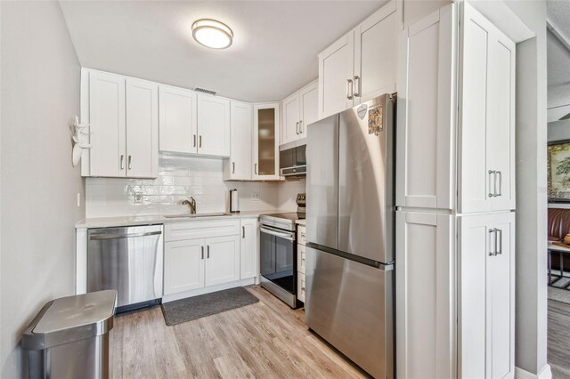 8080 112th St Unit 108, Seminole, FL 33772 - kitchen with appliances with stainless steel finishes, white cabinetry, light countertops, and light wood finished floors
