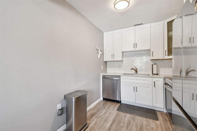 8080 112th St Unit 108, Seminole, FL 33772 - kitchen with dishwasher, backsplash, light countertops, white cabinetry, and light wood-type flooring