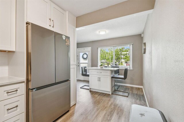 8080 112th St Unit 108, Seminole, FL 33772 - kitchen with freestanding refrigerator, light wood-type flooring, white cabinetry, and light countertops