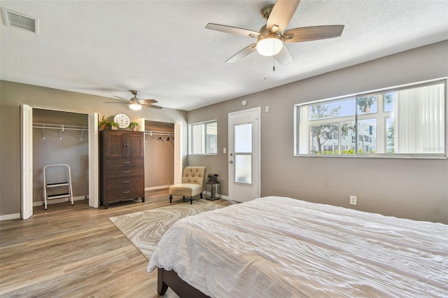 8080 112th St Unit 108, Seminole, FL 33772 - bedroom featuring two closets, light wood-style floors, a textured ceiling, and a ceiling fan