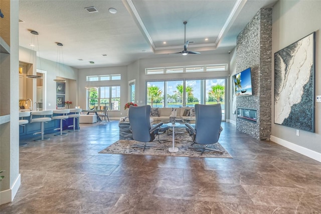 12902 SW 138th Loop, Dunnellon, FL 34432 - living room with a ceiling fan, a stone fireplace, crown molding, and a tray ceiling