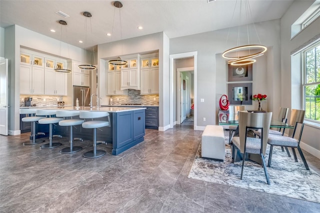 12902 SW 138th Loop, Dunnellon, FL 34432 - kitchen featuring light countertops, backsplash, a kitchen island with sink, glass insert cabinets, and recessed lighting
