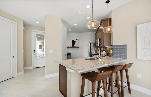 14317 Eagle Branch Dr, Nokomis, FL 34275 - kitchen with stainless steel appliances, a peninsula, a breakfast bar, light stone countertops, and recessed lighting