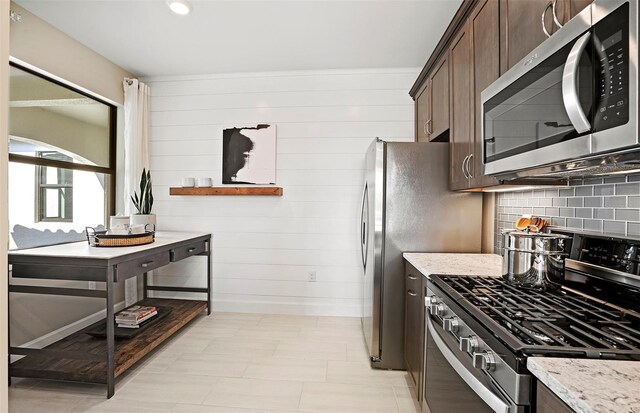 14317 Eagle Branch Dr, Nokomis, FL 34275 - kitchen featuring appliances with stainless steel finishes, dark brown cabinetry, backsplash, and light stone countertops